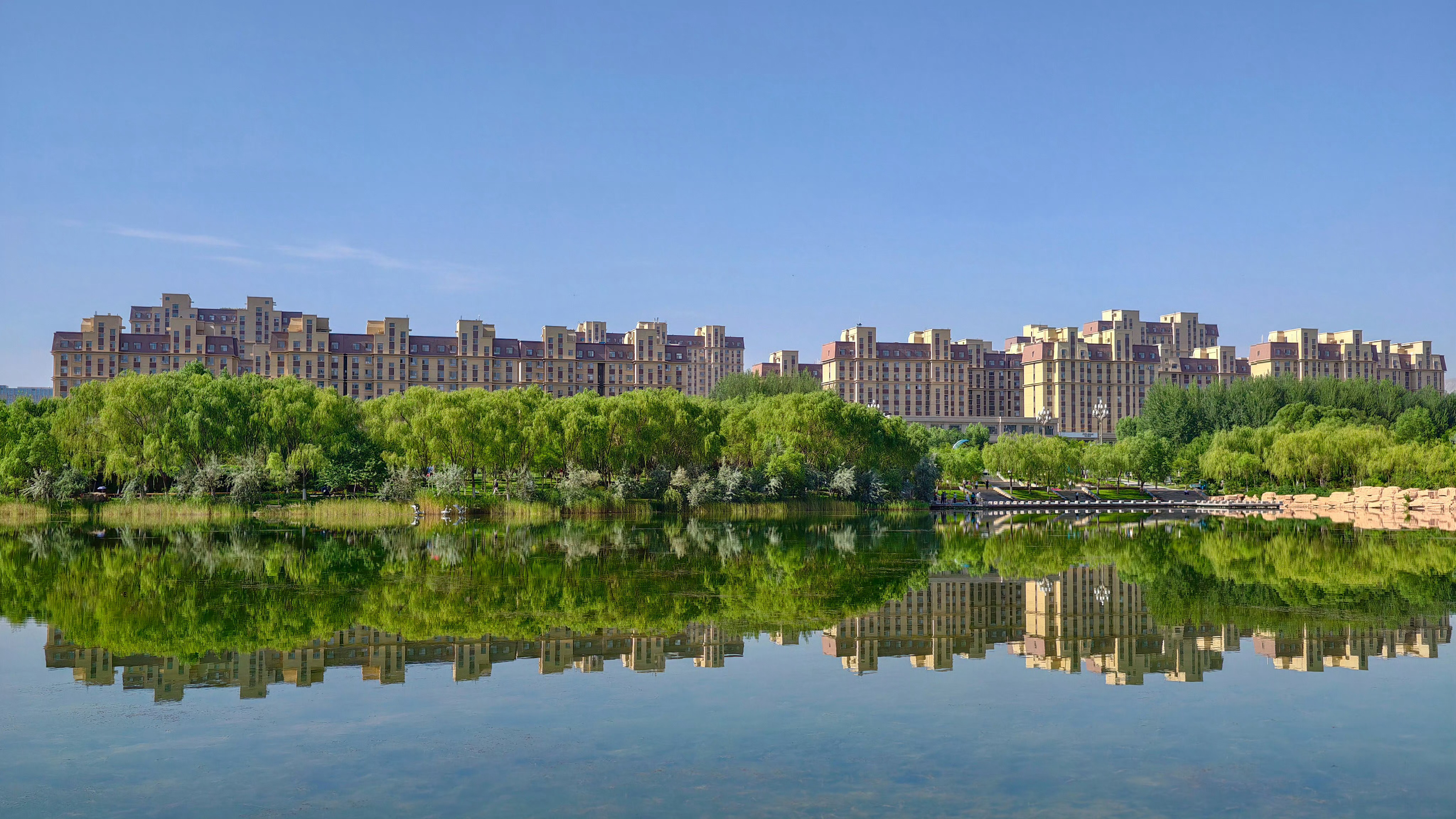 用镜头解锁金昌N种美好，龙首湖公园像金昌写给夏天的一封慢信。湖面接住天空，树影铺