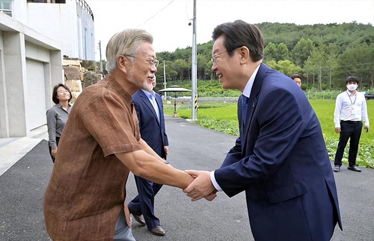 李在明不年轻了，但他和头发胡须都花白的文在寅在一起，就显得他有点年轻。果然鲜花需