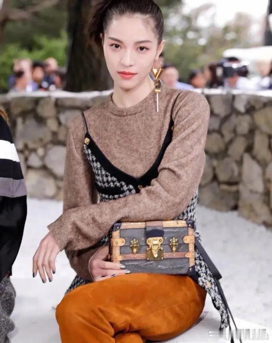钟楚曦扎气质丸子头，身穿毛衣叠加千鸟格吊带搭配橘棕色裤子，尽显高级优雅范儿 