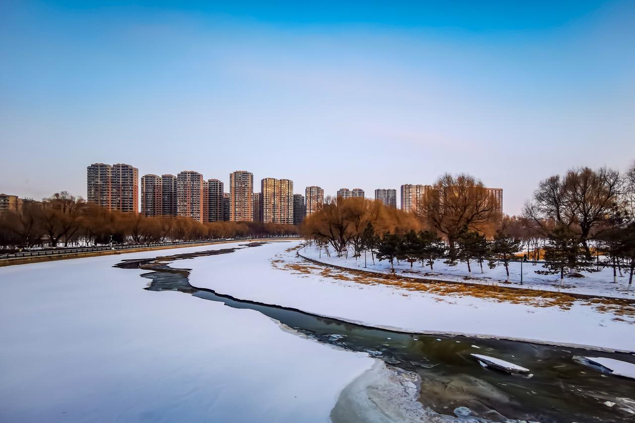 数九寒天，河道静卧如一卷摊开的素宣。雪为絮，冰为骨，天地以冻笔皴出茫茫银白。唯中