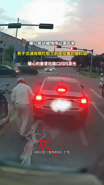 路口等红灯，骑手悄悄帮前车取下塑料袋

红绿灯下，车流缓缓停下。前车车尾缠上塑料