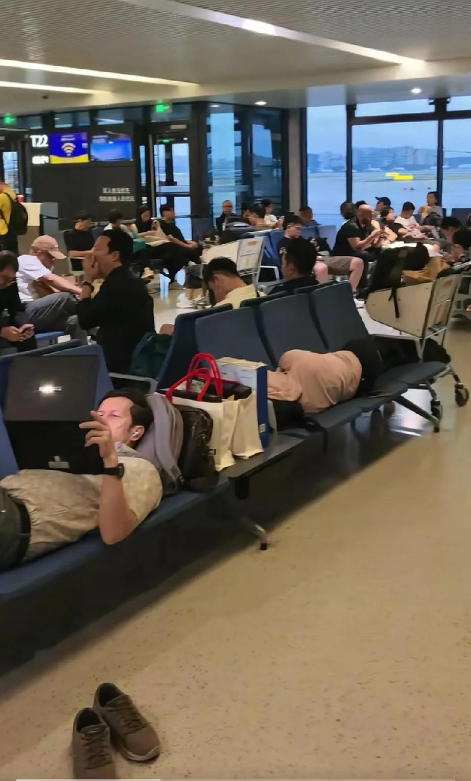 某地机场，两外国人脱鞋躺在座椅上霸占了六个座位，一个在睡觉，一个在专心的玩着电脑