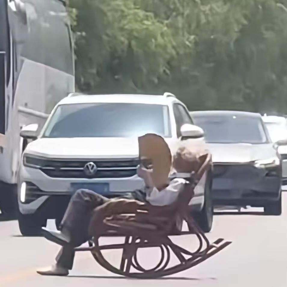 陕西大爷把马路当自家客厅，路中间摆躺椅摇着扇子晒太阳，过往车辆吓得纷纷急打方向避