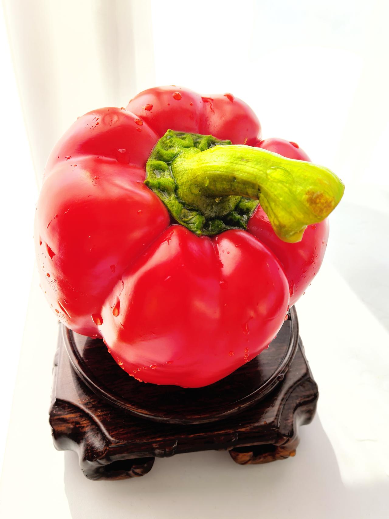 千问是这样配文的：鲜艳的红椒，宛如艺术品般置于木质底座之上，晶莹的水珠点缀其上，