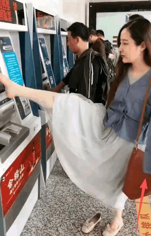 杭州地铁站，售票机前。 一个女子抬起右脚，脚趾在屏幕上快速点选，动作流畅得让人惊