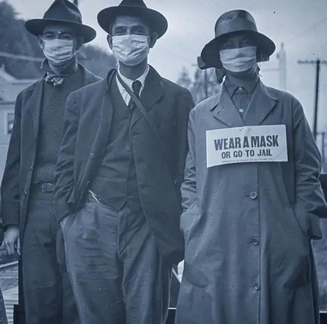 1918年西班牙爆发大流感，街上戴口罩的男士身上挂着牌子，写到：“要么戴上口罩，