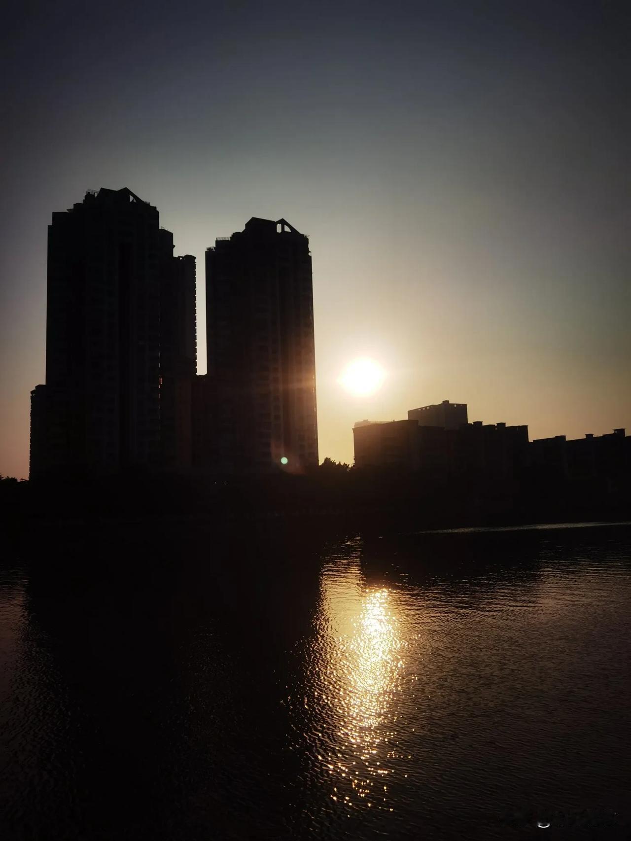 分享一张最近随手拍的照片落日余晖，江畔别样美！高矮楼缝视角下的夕阳，逆光之美，太