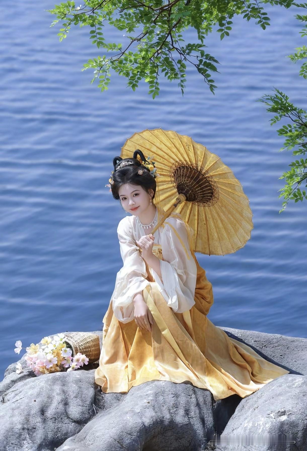 像是从山水画里走出的仙子。
身畔是碧波荡漾的江水，
身后是连绵起伏的青山。
不需