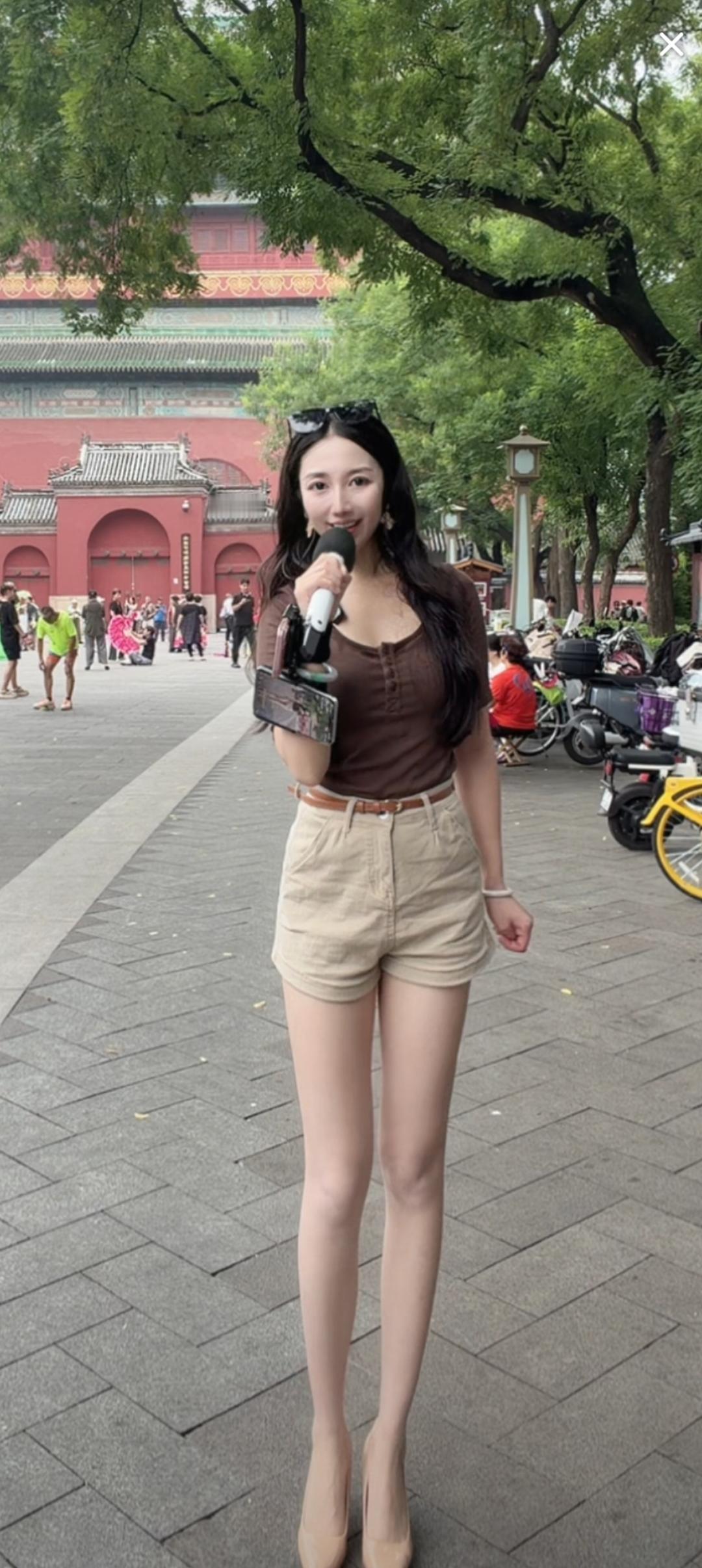 一位美女在街头拿着麦克风唱歌。