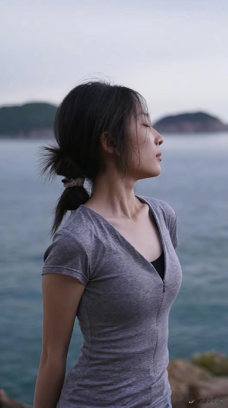 海边微风拂面，少女轻闭双眼，享受宁静时光。