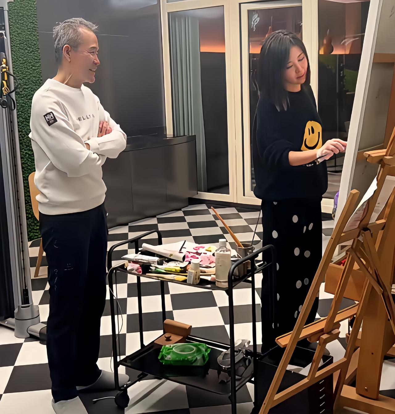 王石与田朴珺的旧照，田朴珺在家里画画，王石站在一旁观看，满脸的笑容，美滋滋的。
