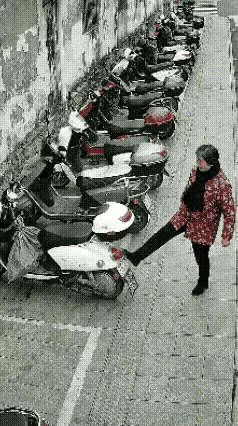 自作孽不可活。女子闲的没事干，脚发痒痒，踢翻一辆电动车又踢一辆，当他踢第二辆车时