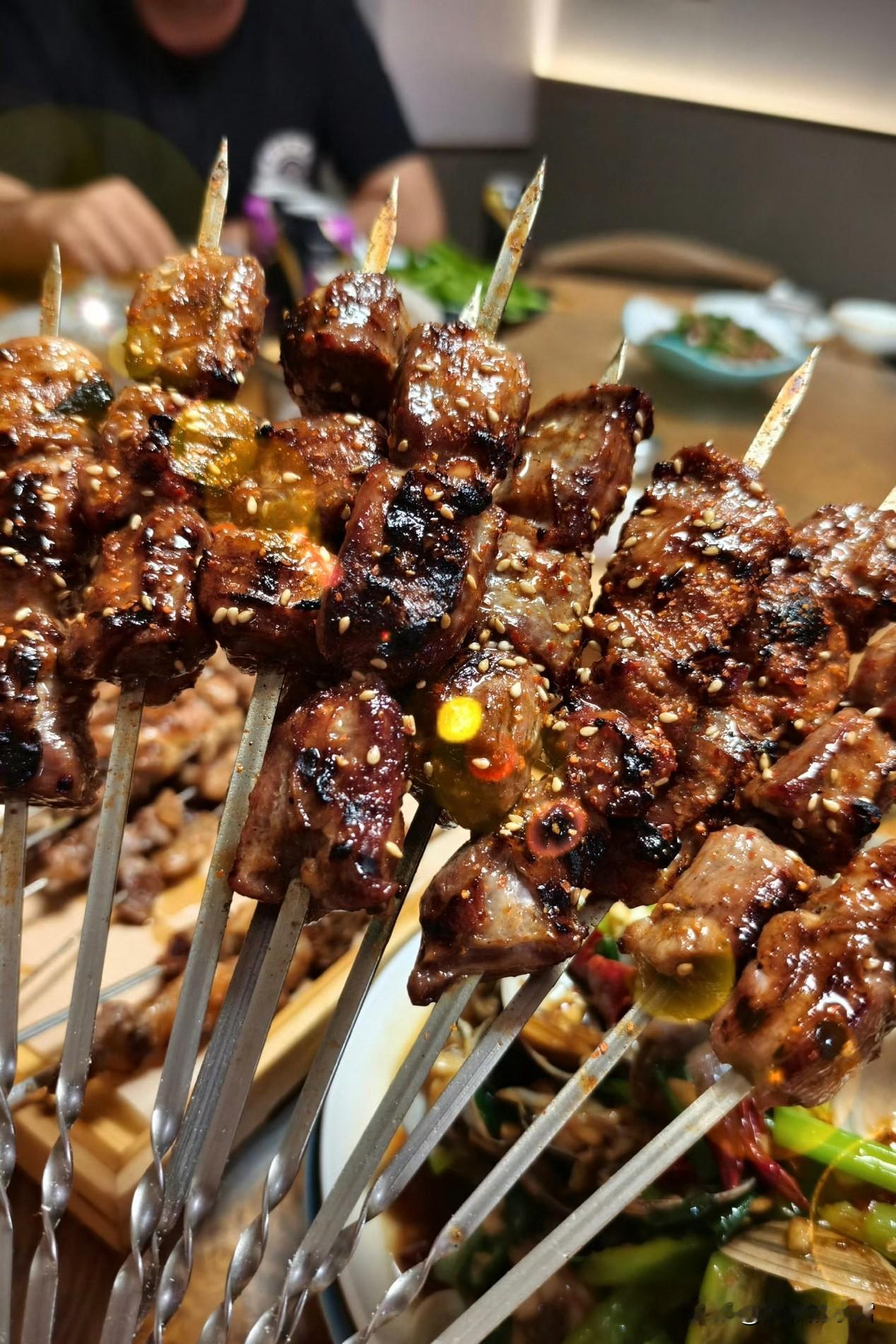 烤串裹着焦香的油光，芝麻和调料在炭火气里跳着香；肉卷烤得油润透亮，连空气都浸满了