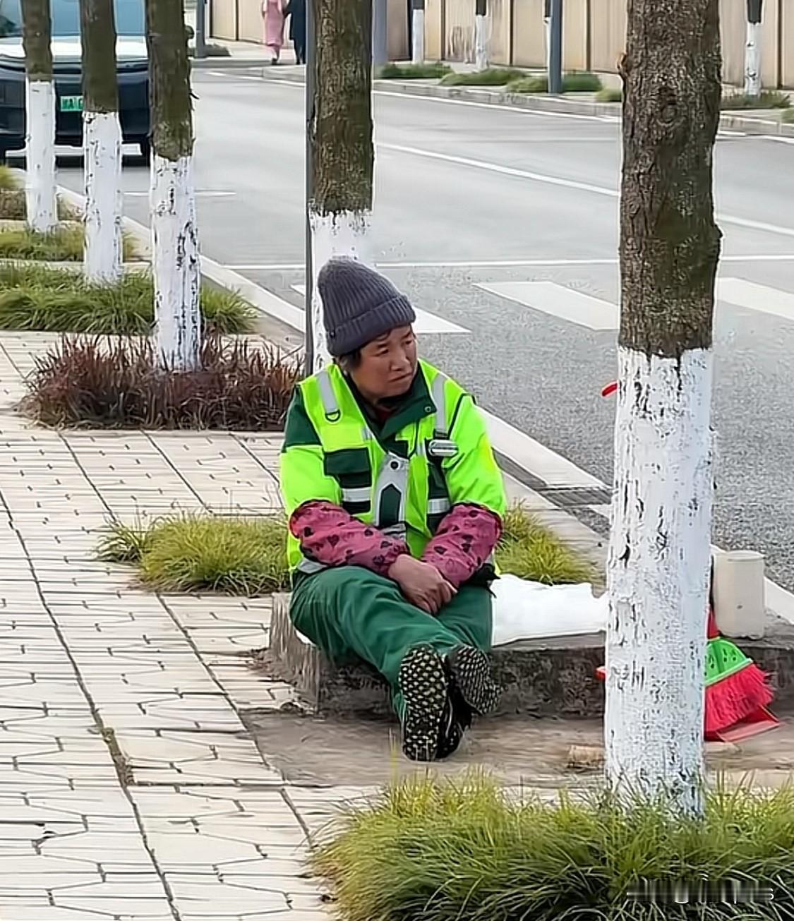 网上一段视频，一名环卫工人阿姨，坐在地上，看着路对面的同龄人在跳广场舞。网友猜测