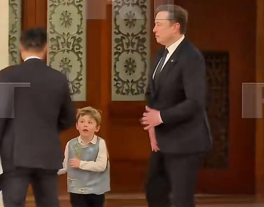 随同美国总统特朗普访华的美国企业家马斯克携幼子现身人民大会堂，孩子背着一个中国风