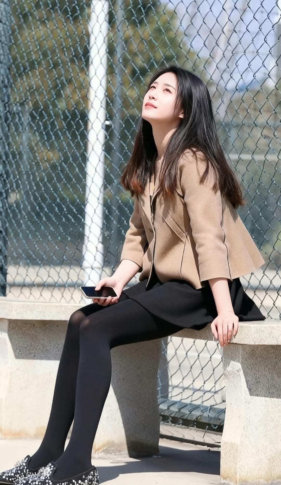 阳光下的优雅时光，咖啡色外套与黑色裙子的完美搭配，尽显都市女性魅力。