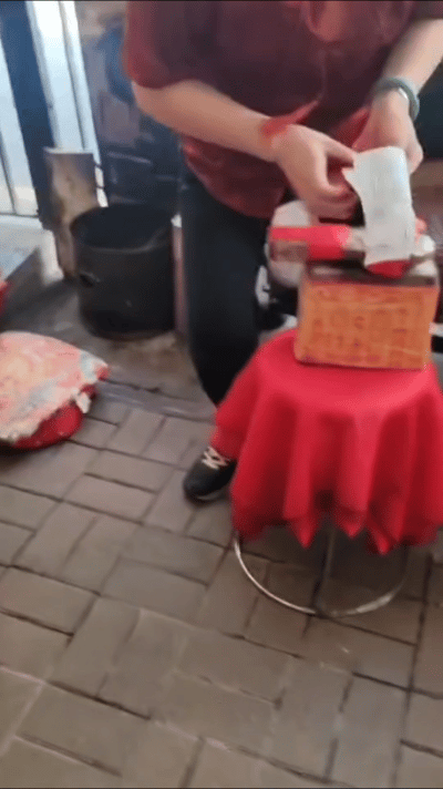 香港湾仔区老人一只手捏着两张符纸，另一只手拿着拖鞋，嘴里念念有词一番后便坐下，接