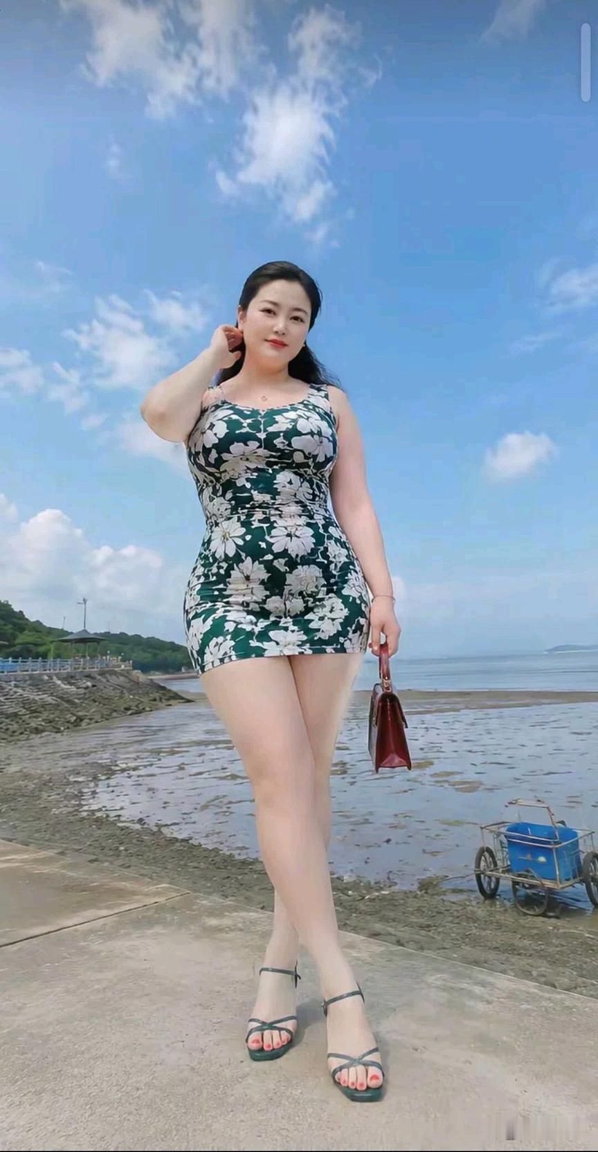 海边美女穿花裙，手拿小包晒太阳。