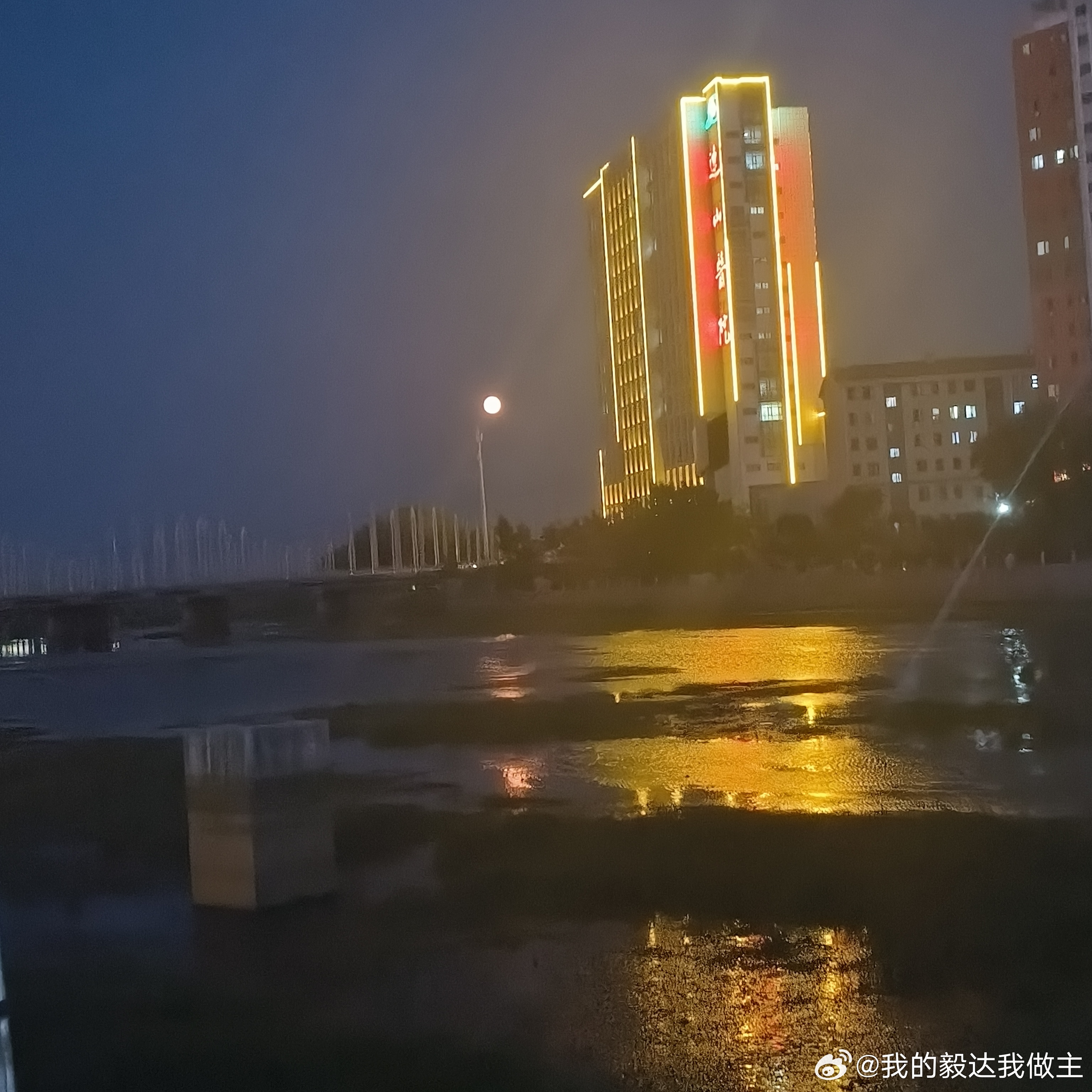 夜雨后的城市意外浪漫✨霓虹倒映在积水里，像打翻的调色盘🎨桥边微光摇曳，水波轻漾