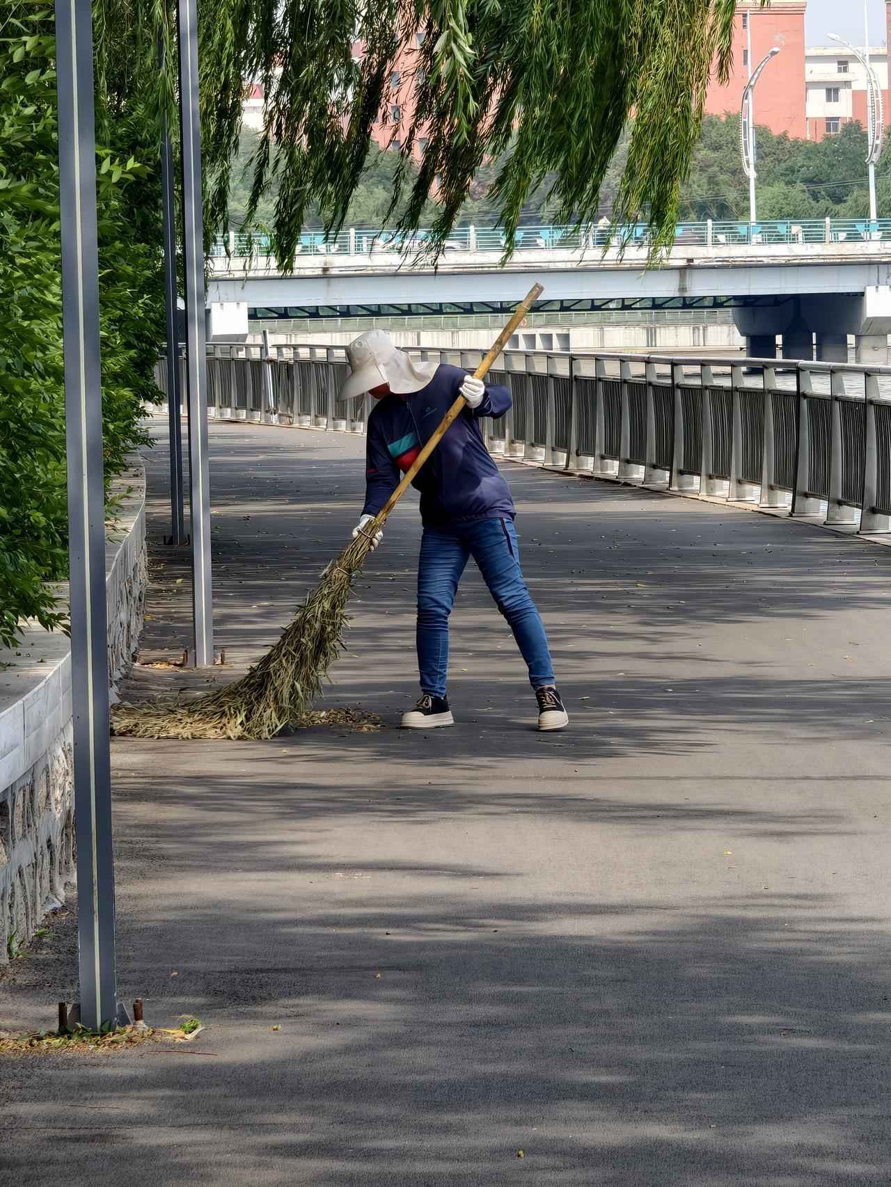今天阜新最高气温达到32℃，烈日之下，细河河畔的环卫工人正低头清扫着人行步道。他