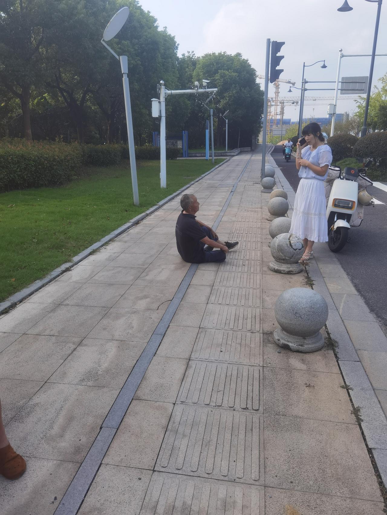 洋泾湖西侧，越王路上，坝里金大桥北端，一老者摔倒，一白衣女子报警，为好人点赞。路