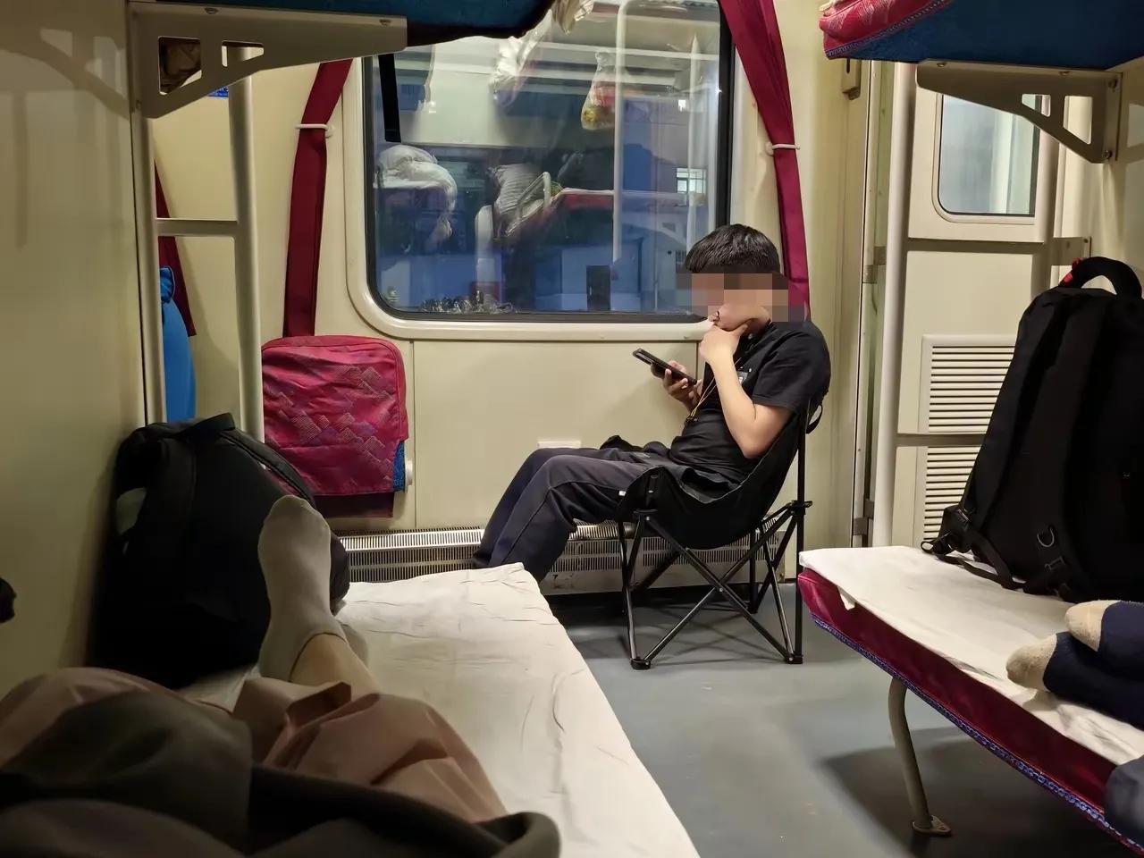 这哥们个性特点太鲜明了，卧铺车厢的小翻板凳不坐，自带小凳坐在下面，看手机看到11