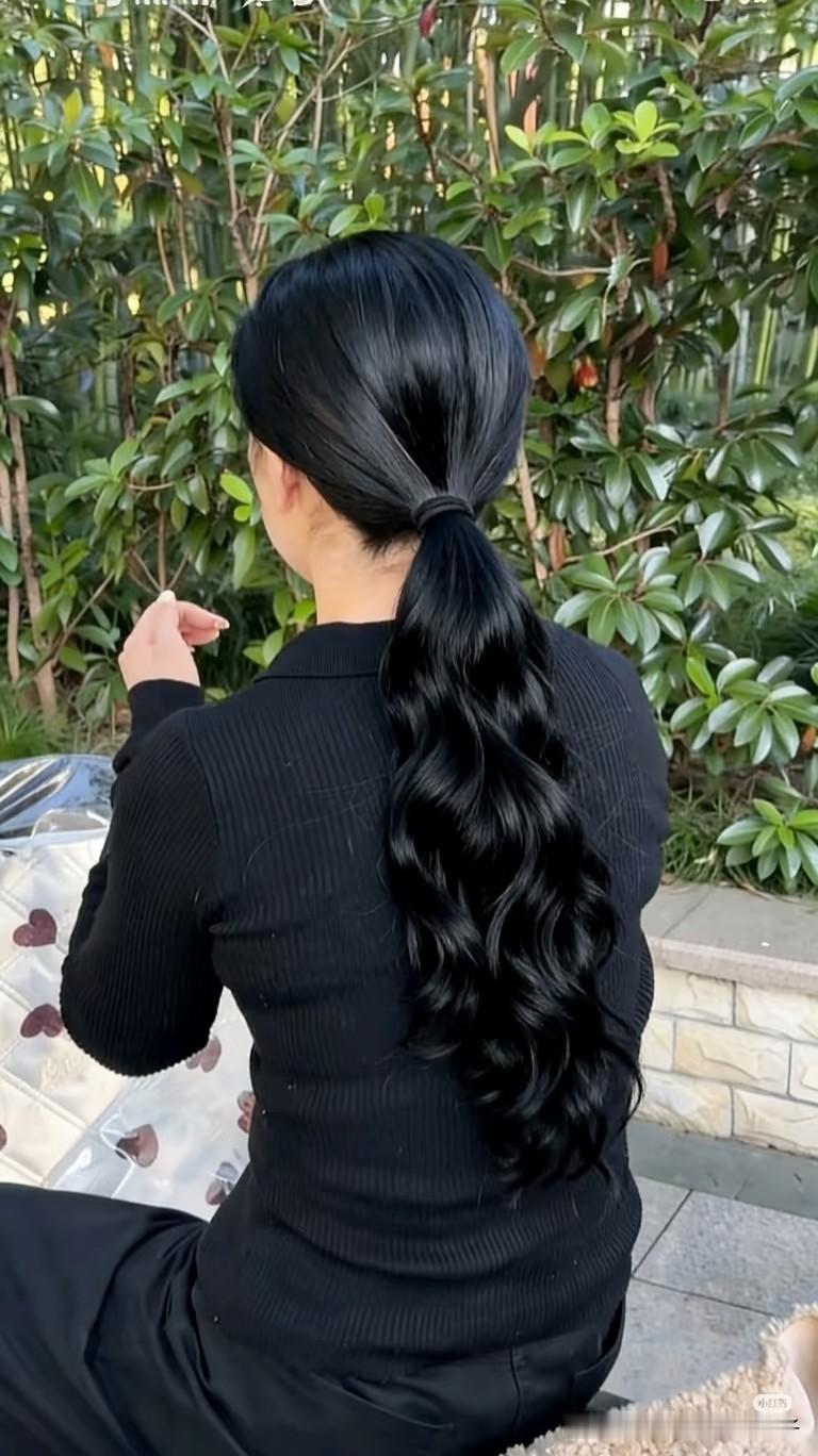 黑发在风里漾开柔润的卷，像浸了光的绸缎，连背影都裹着松弛的温柔。