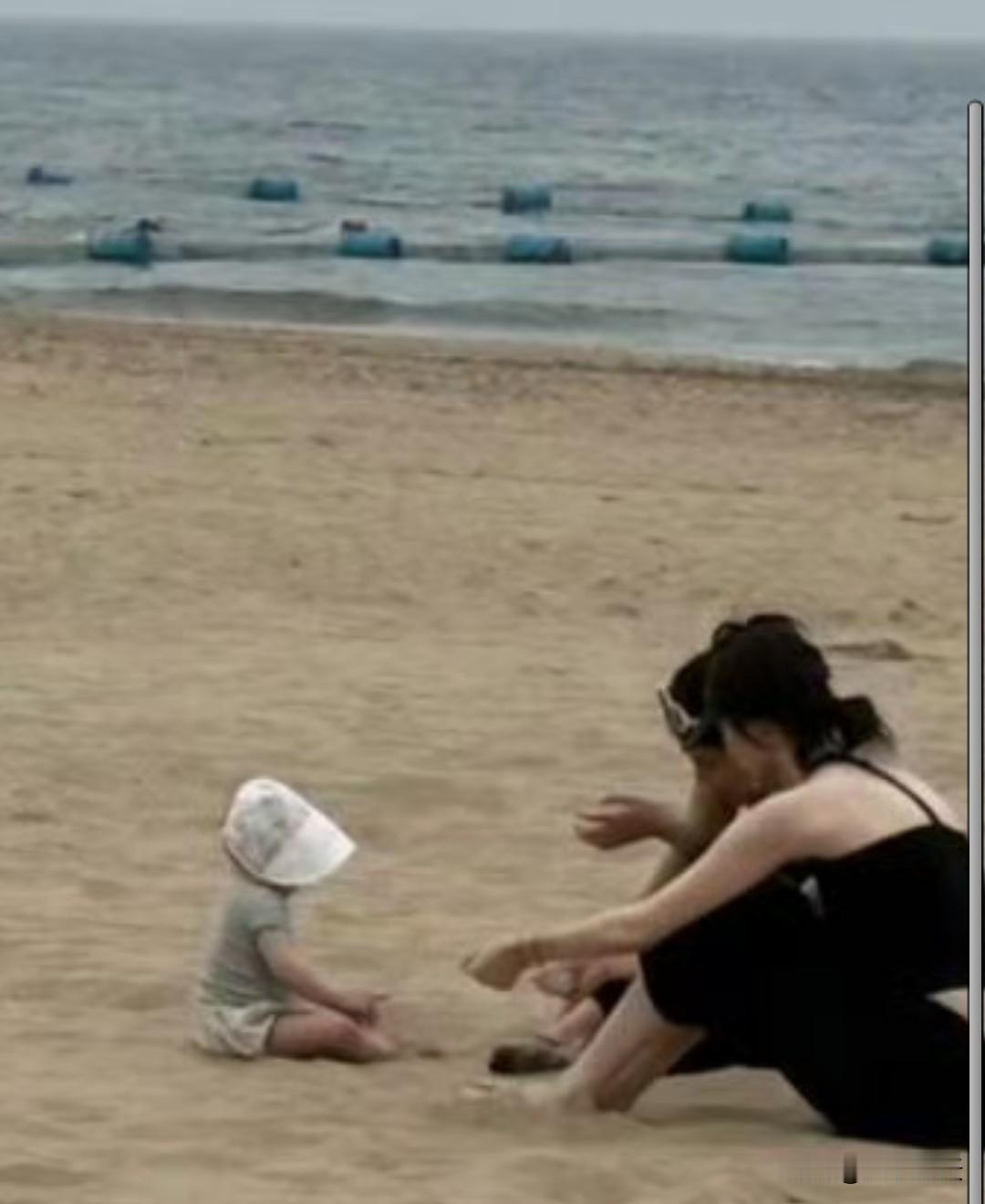 陈伟霆和何穗带1岁儿子现身秦皇岛海边度假，何穗坐在沙滩上，逗着儿子玩，看起来好有