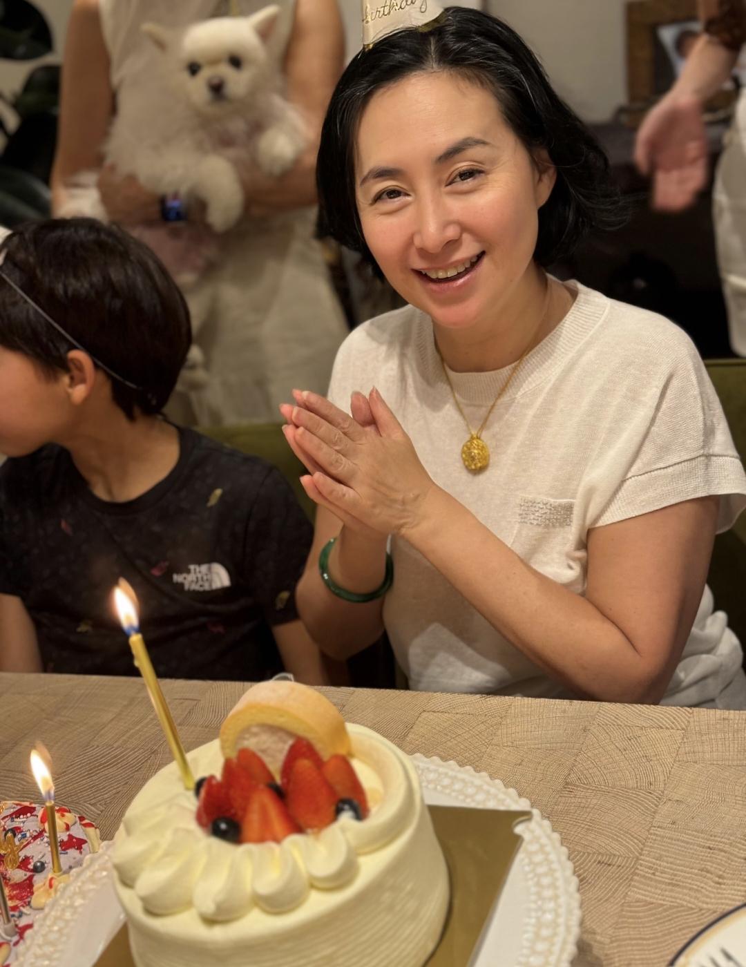 64岁何超琼和干女儿曾昭仪一家庆祝生日，她穿着一件简单的白色短袖上衣，脖子上戴着