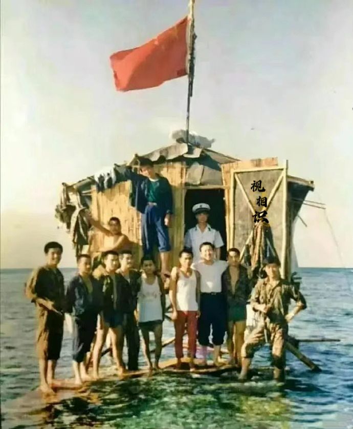 1988年，南沙群岛东门礁，守礁官兵们的合影照片，他们站在简易的高脚屋上，这是用...