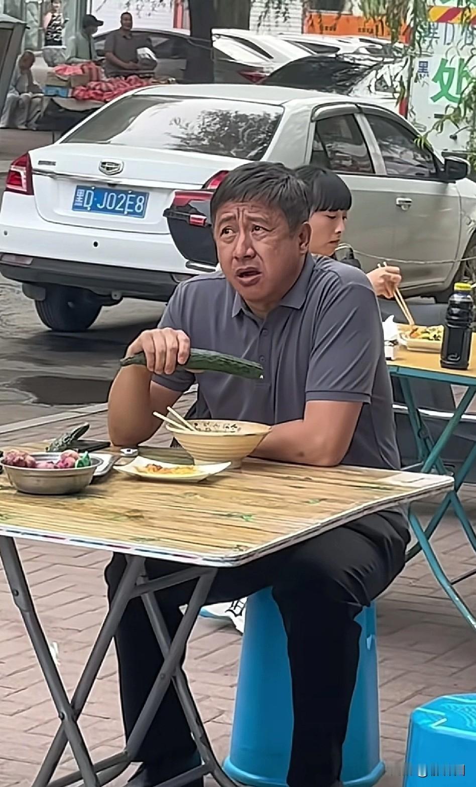 著名演员张国强被偶遇在路边摊吃6元面，并啃食生黄瓜，身形发福且衣着朴素，满头花白