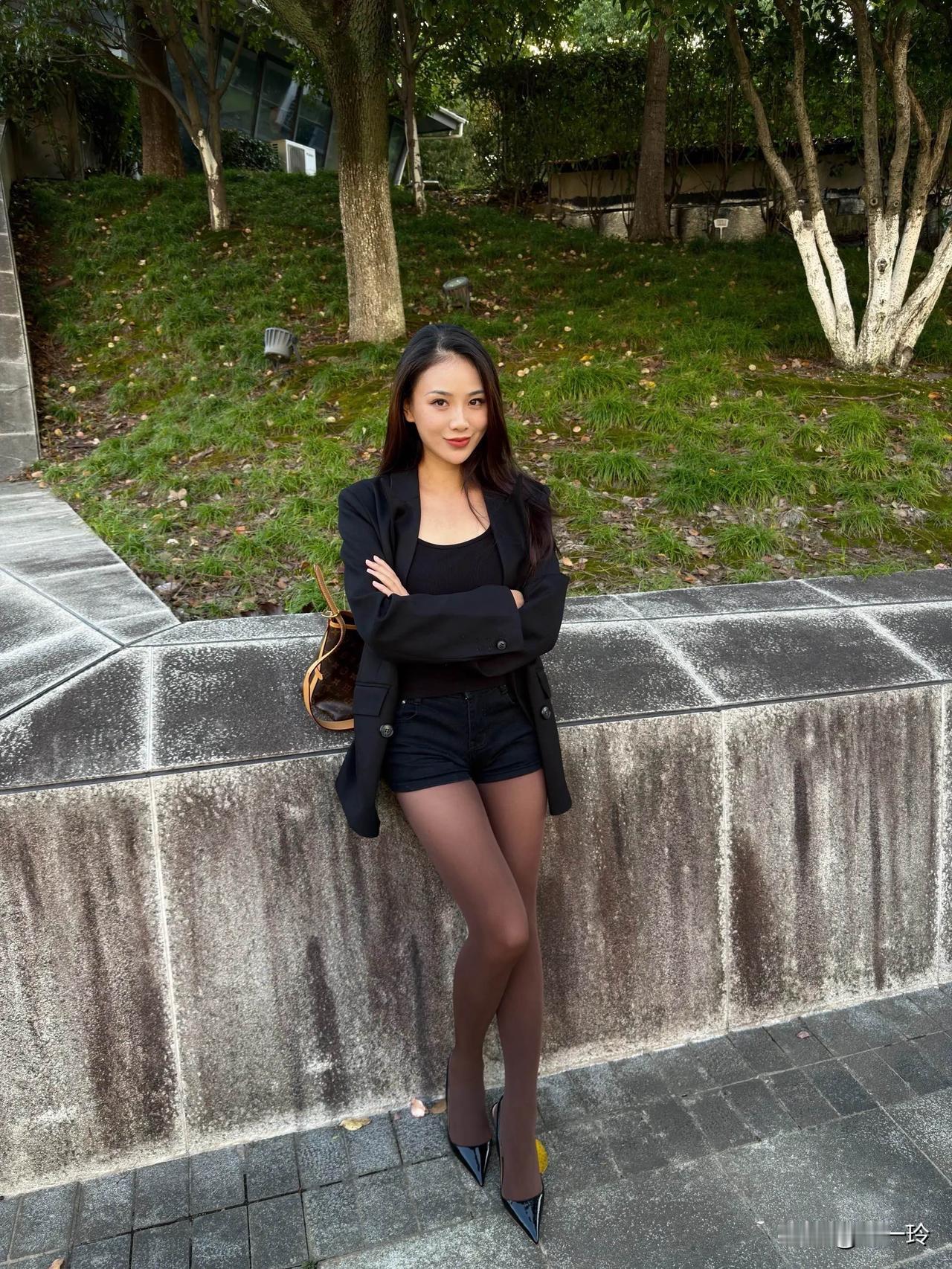 美女坐在公园长椅上，手拿LV包。