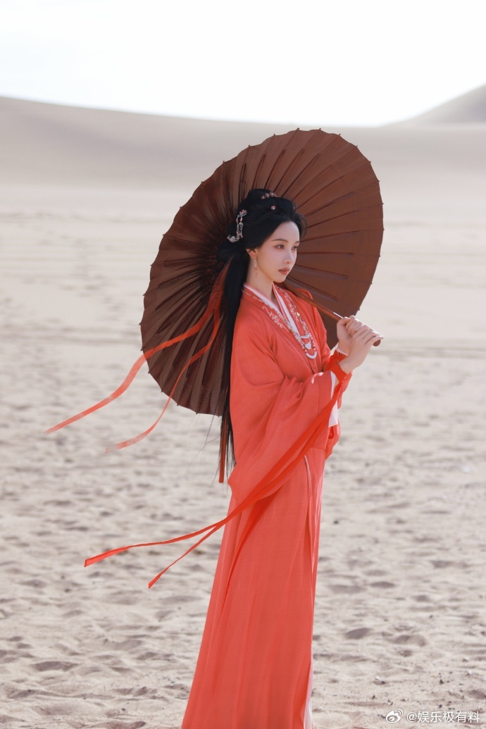 陈都灵红衣撑油纸伞陈都灵大漠撑伞神图 风沙漫过旷野，红衣独留暖意，陈都灵手握油纸