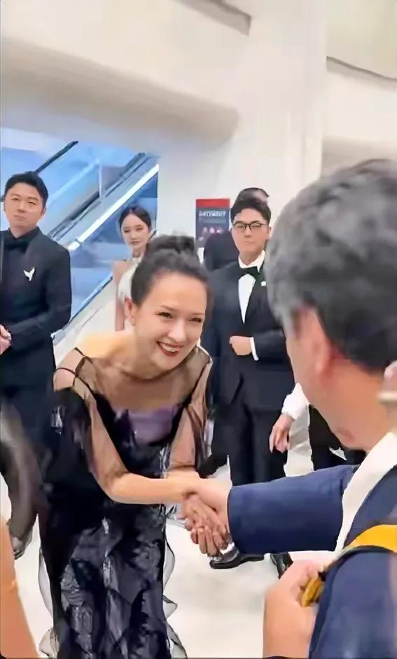 章子怡在戛纳电影节上腰杆弯了。照片中的章子怡偶遇日本导演枝裕和，见面握手打招呼本