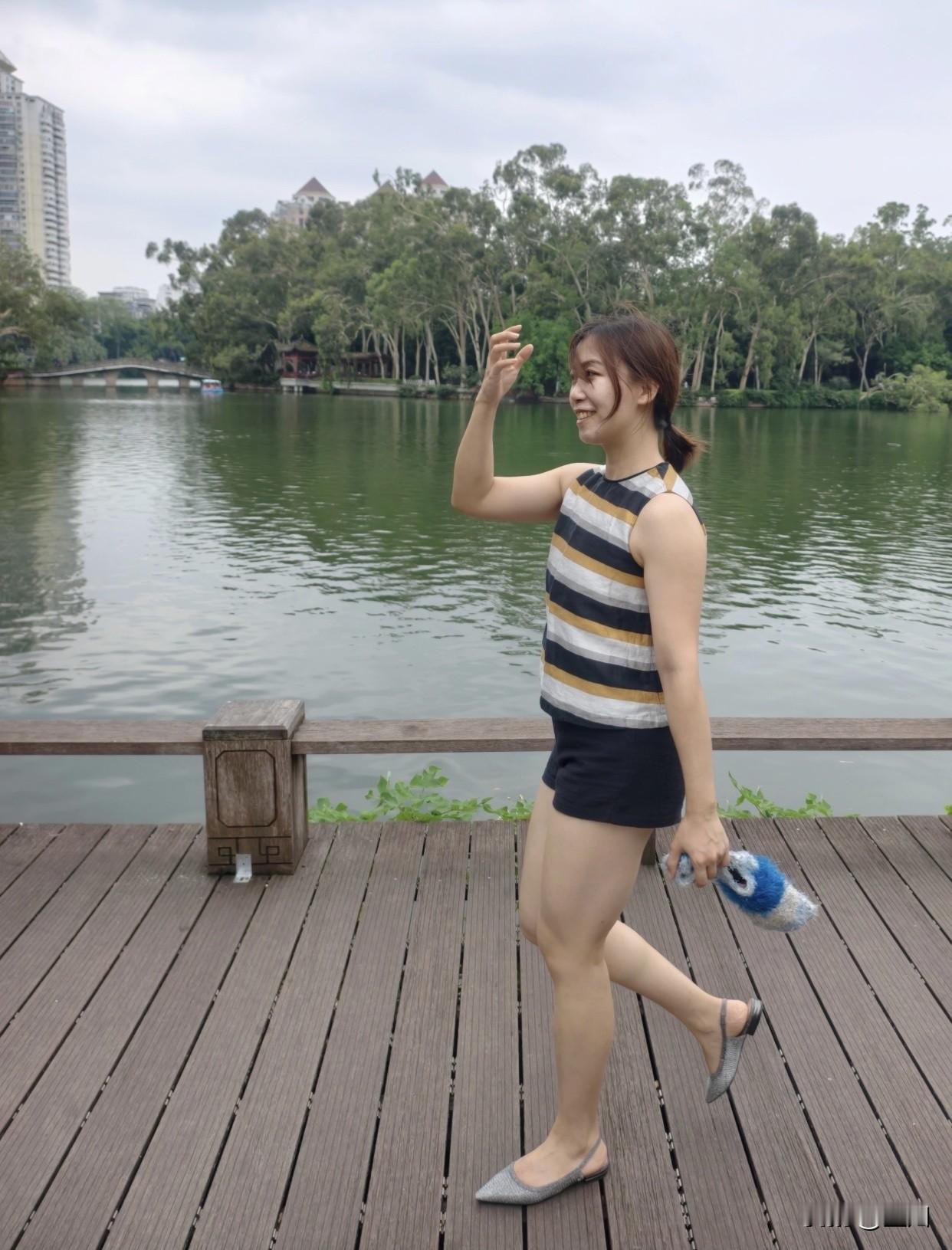 每日搭配分享·时尚穿搭一位女生在湖边散步，看着手机。