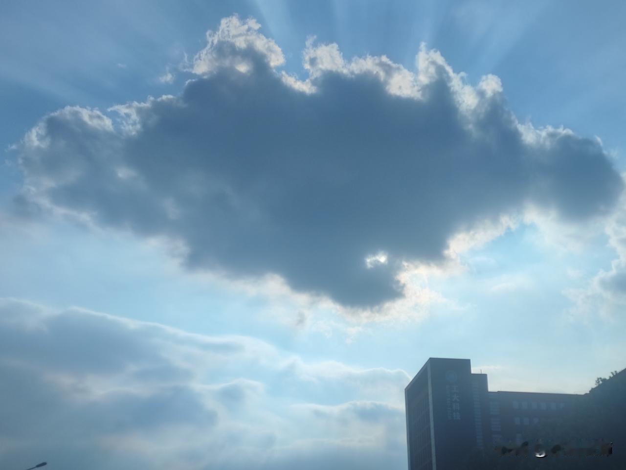 云层像一块柔软的幕布，将夕阳的光芒大部分遮挡，却又在边缘与缝隙中透出数道清晰的光