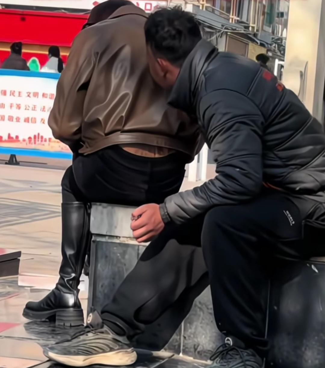 陌生男子悄悄坐在女子身后，贴近偷偷闻女子。拍摄者称，自己发现一女子坐在路边凳子上