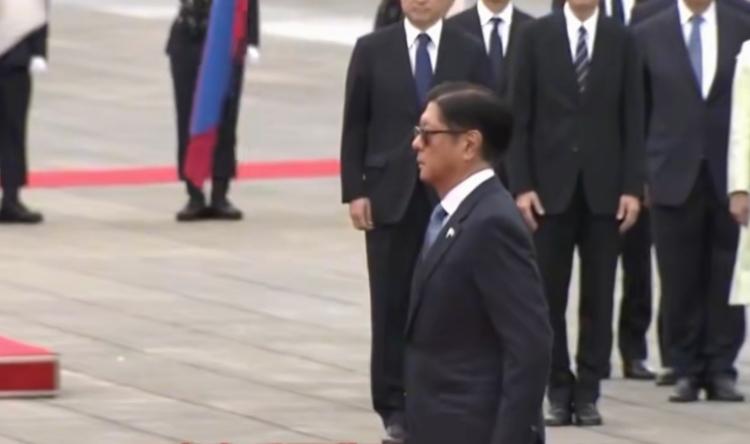 带着墨镜，站立的规规矩矩，不像菲律宾总统小马科斯要检阅日本仪仗队，倒像是日本要检