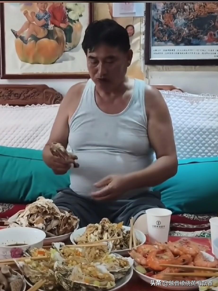 大衣哥和一群人在视频中对着大虾烧鸡埋头干饭，嘴里还发出哼哼的笑声，周围一群人也在