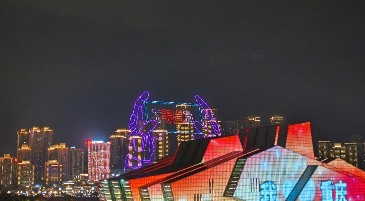 无人机以夜空为画布，勾勒出各种各样的图案，山水之城，山茶花开，等画面出现的时候，