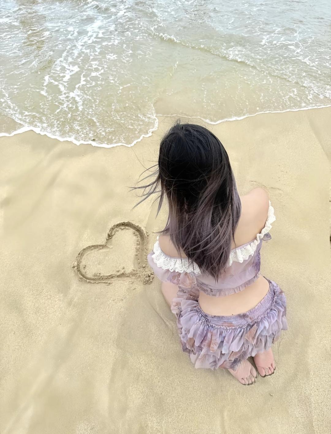 上周在三亚湾看日落，刚好撞见穿白连衣裙的女孩蹲在湿沙滩上画心。
橙红色的落日把海