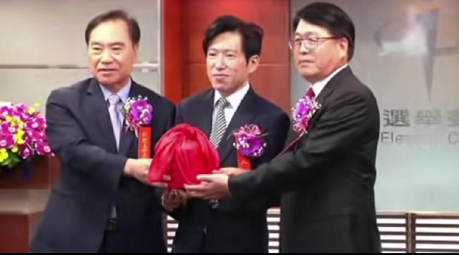 台湾地区的行政官员真土，胸上还戴个小花，真幼稚，这个场景总感觉和我们过去80年代