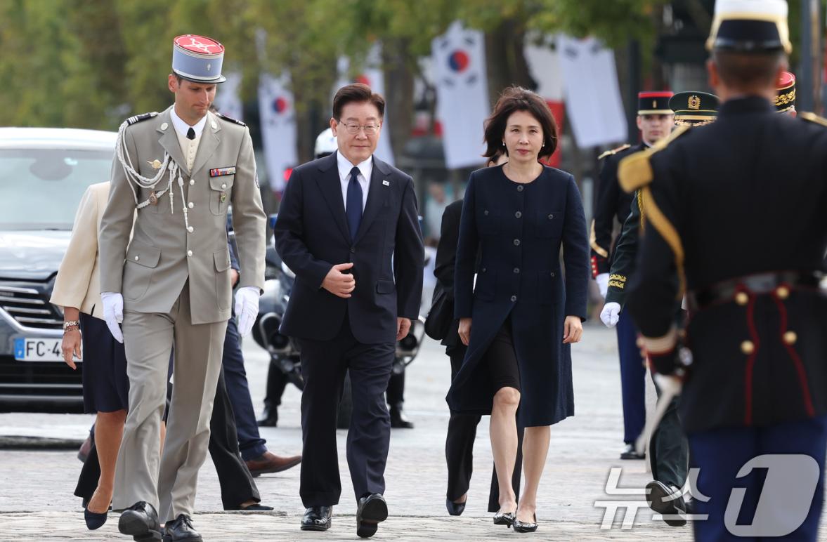 9月8日李在明带着妻子到巴黎凯旋门为无名烈士墓敬献花圈，韩国第一夫人穿着黑色风衣