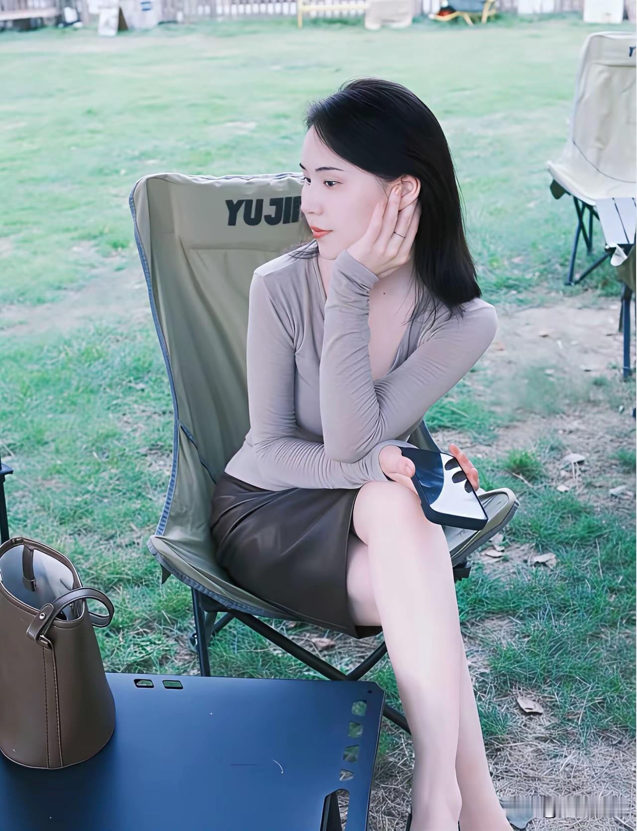 妹子坐在椅子上，玩手机，好悠闲。