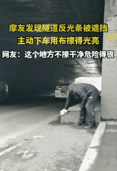 太暖了！一位摩友，在隧道里停下来，拿着块布仔仔细细擦着反光条。那些条子被灰尘盖得