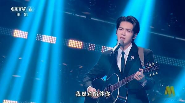 于适吉他弹唱亲爱的小孩湾区升明月晚会正在进行，抱着吉他弹唱《亲爱的小孩》，声音暖