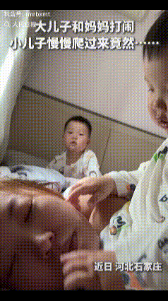 暖心！河北石家庄，妈妈和哥哥在床上玩闹，故意装出被欺负的样子。一旁还在爬行的弟弟