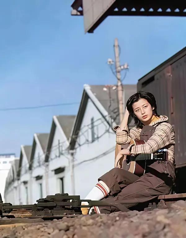 这是当年山口百惠在日本的铁路边坐在路基上休息，那时候上口百惠好清瘦，怀中还抱着一