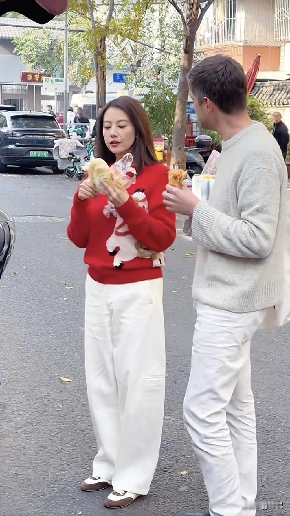 在成都玉林综合市场的街头，高圆圆身着红色毛衣搭配白色阔腿裤，和身旁的友人一同品尝