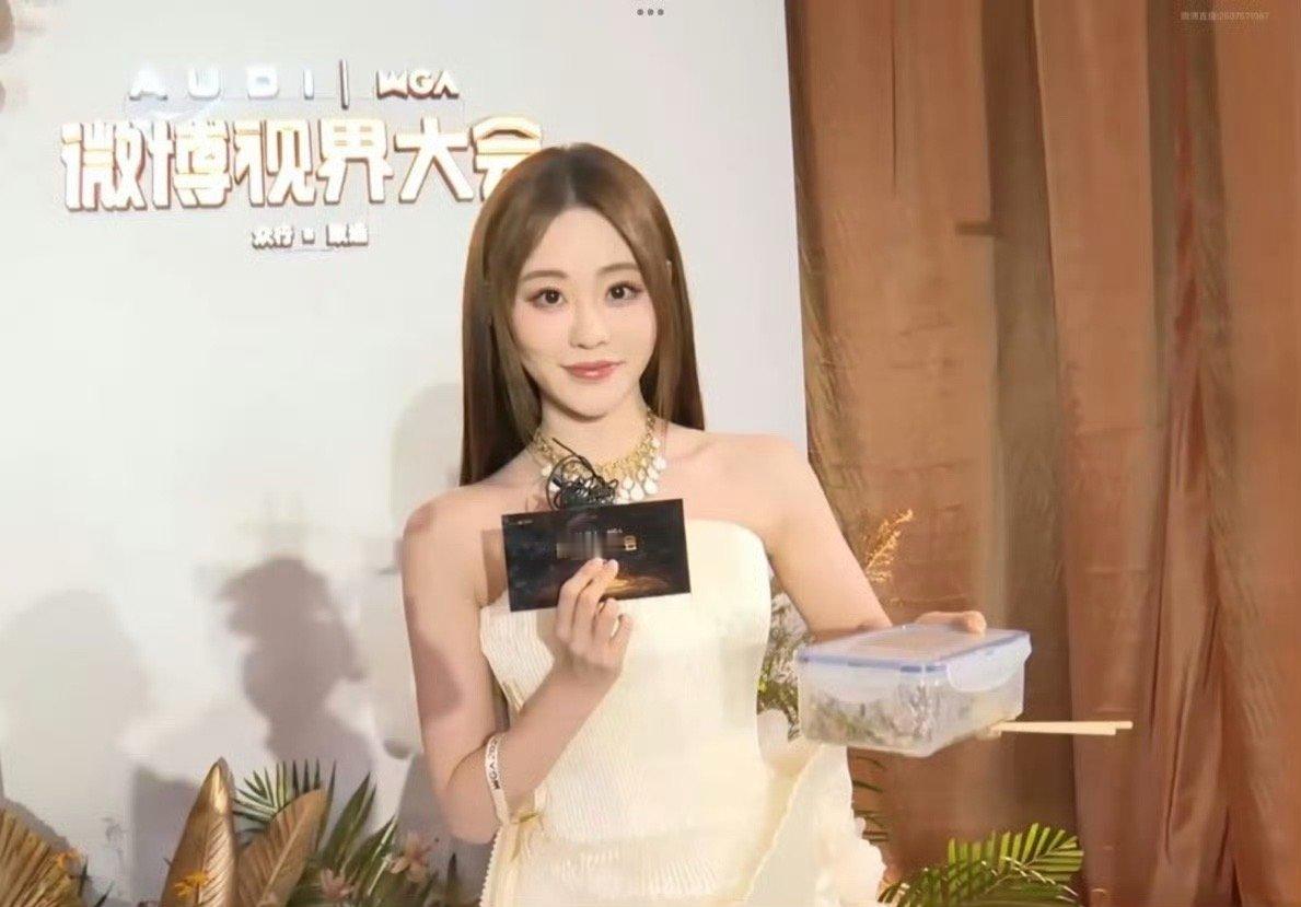 祝绪丹大袜子你咋端着烤肉就来了 祝绪丹在红毯上身着白色礼服，手持一盒齐齐哈尔烤肉